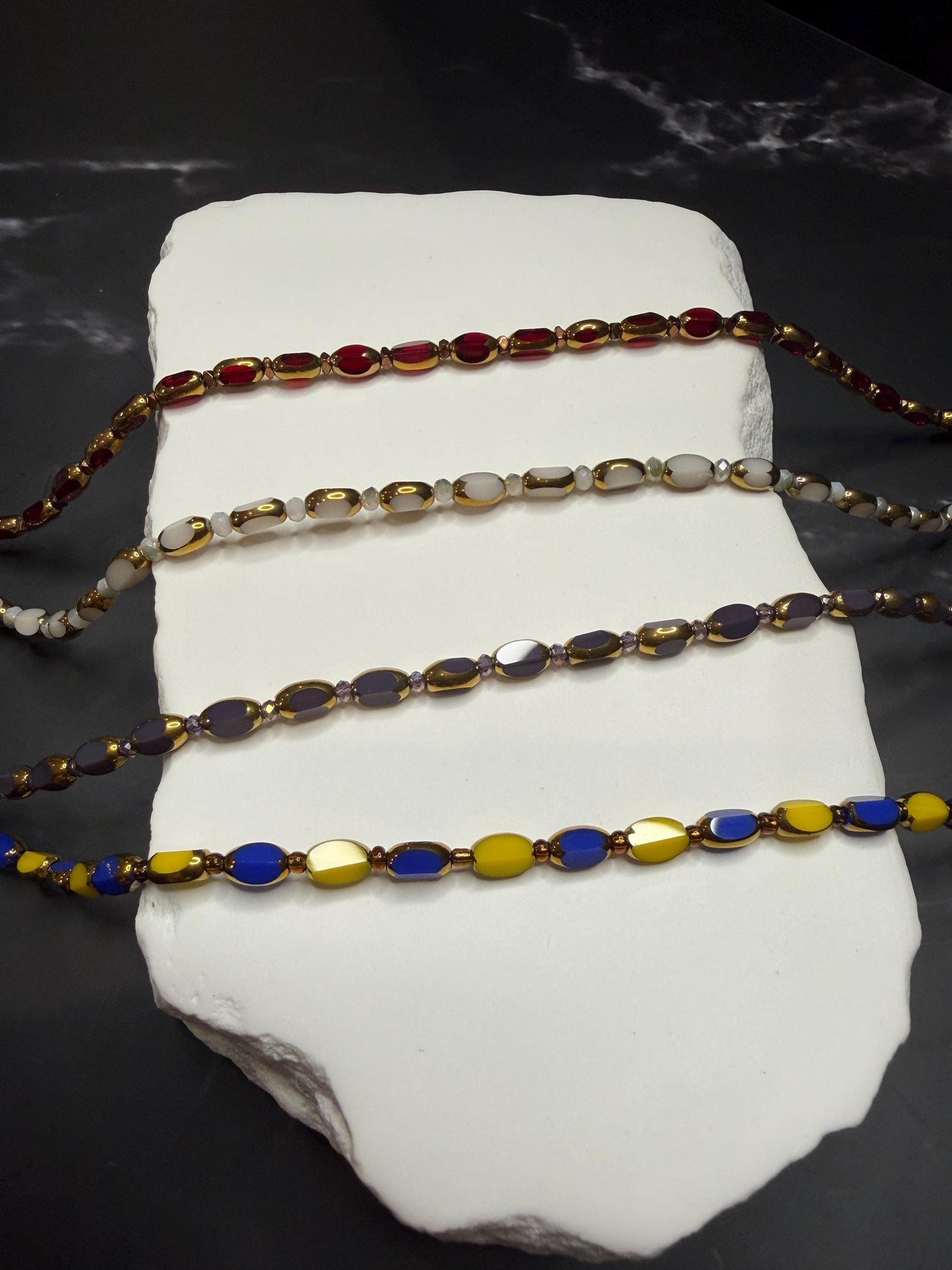 Set of colorful beaded bracelets on a white stone surface with a dark background