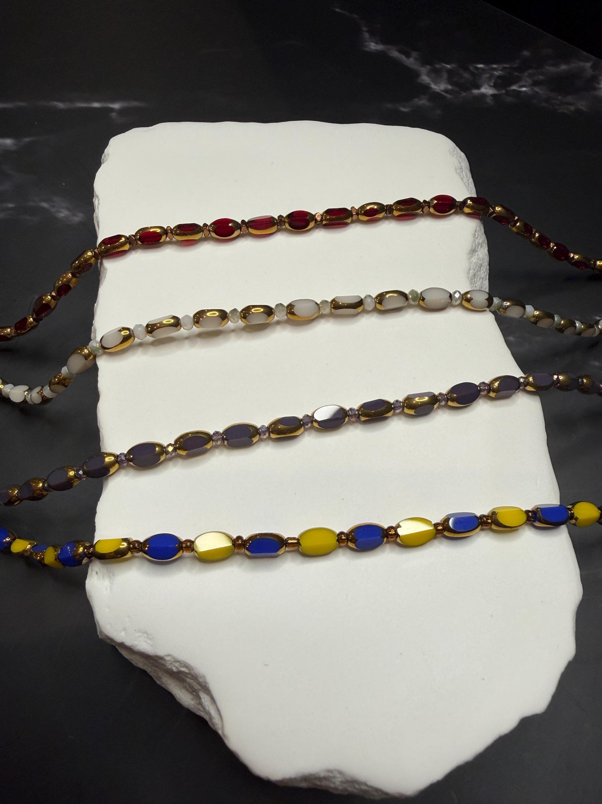 Set of colorful beaded bracelets on a white stone surface with a dark background