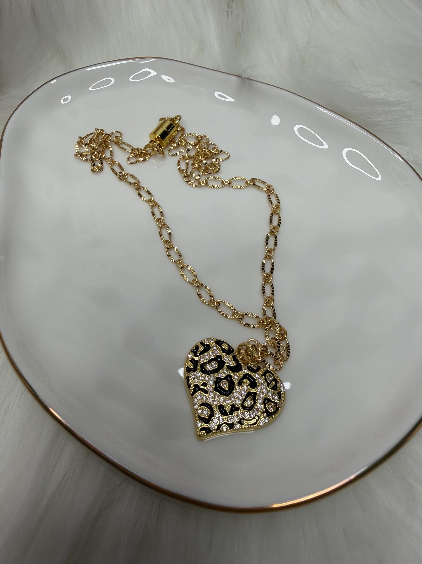 Gold necklace with a heart-shaped pendant on a white surface