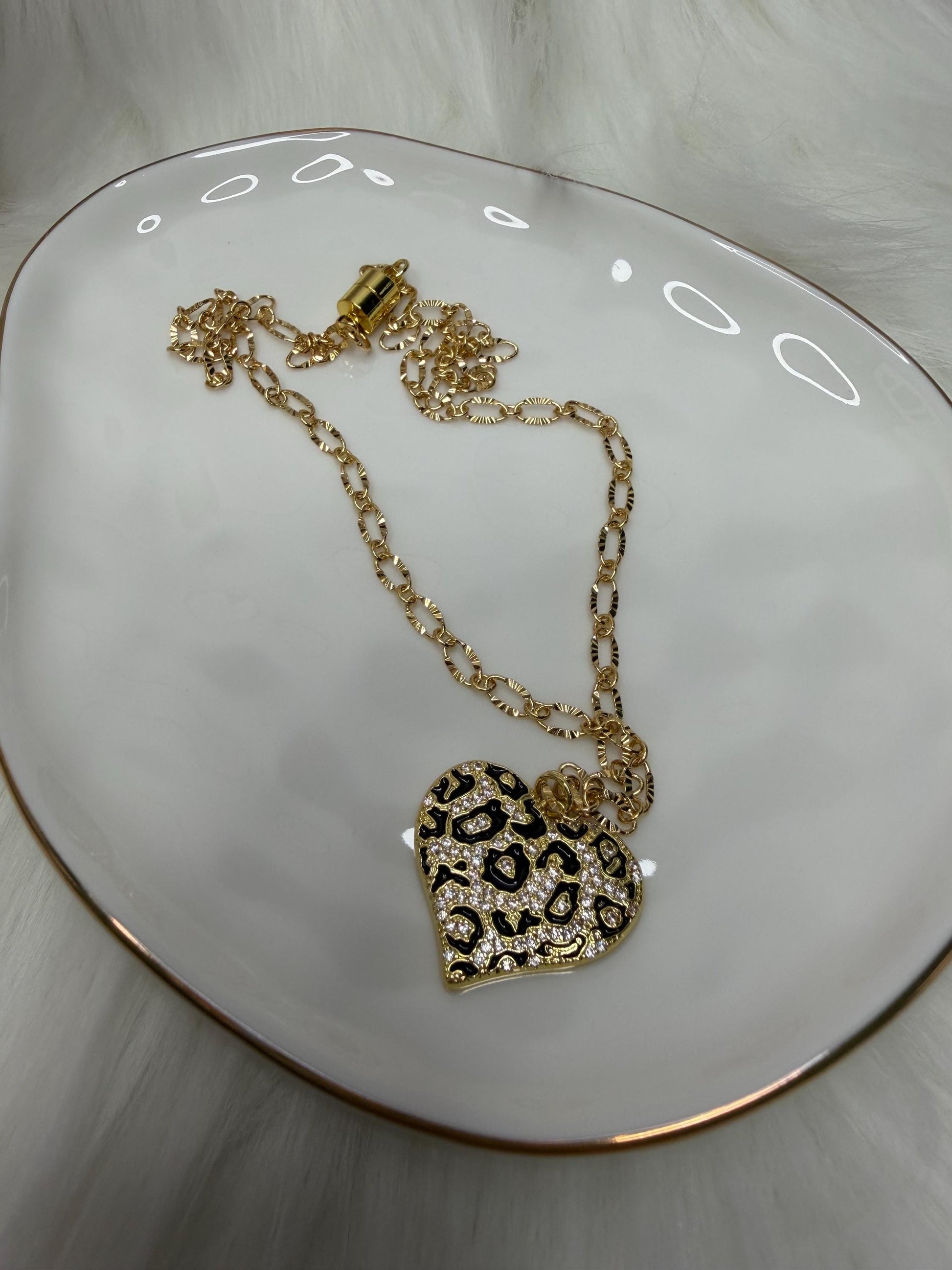 Gold necklace with a heart-shaped pendant on a white surface