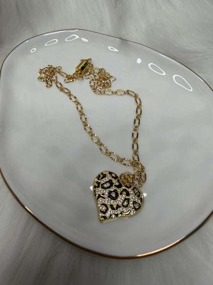Gold necklace with a heart-shaped pendant on a white surface