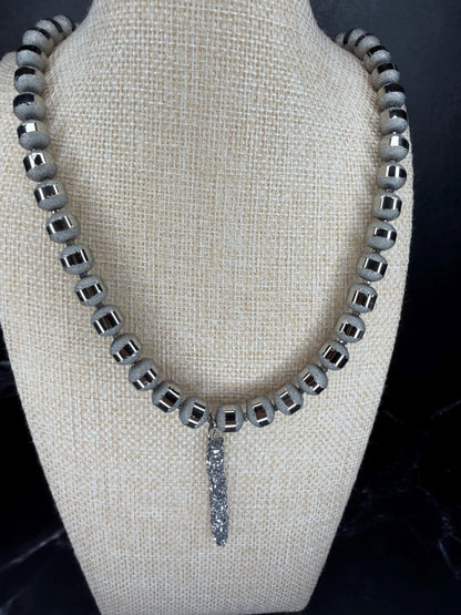 Necklace with square beads and a dangling crystal on a mannequin bust.