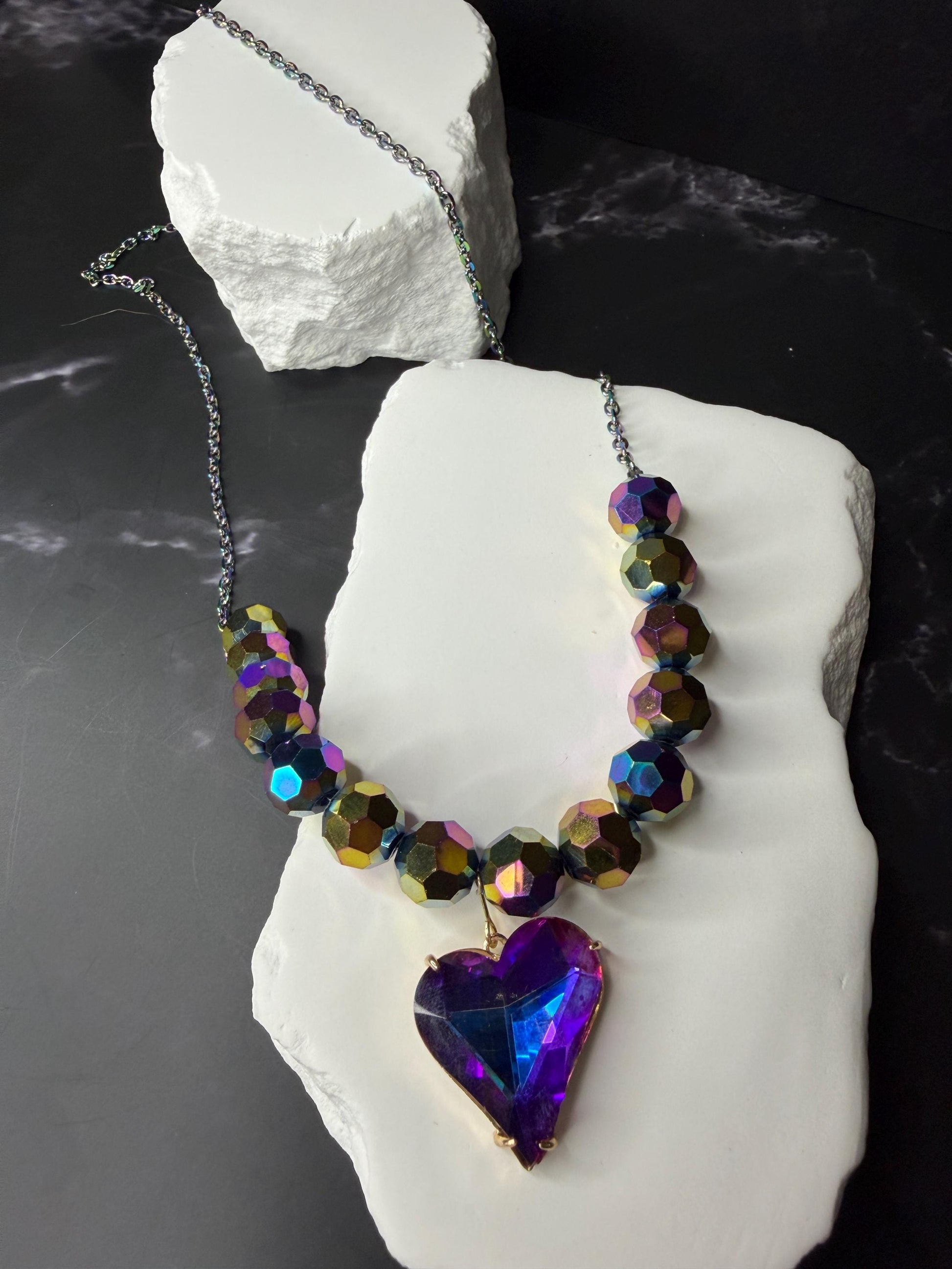Necklace with heart-shaped k9 crystal pendant on a white stone block against a dark background