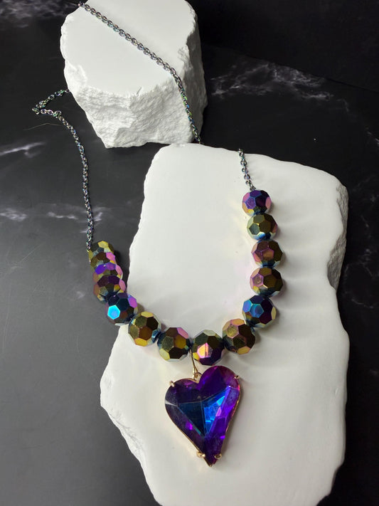 Necklace with heart-shaped k9 crystal pendant on a white stone block against a dark background