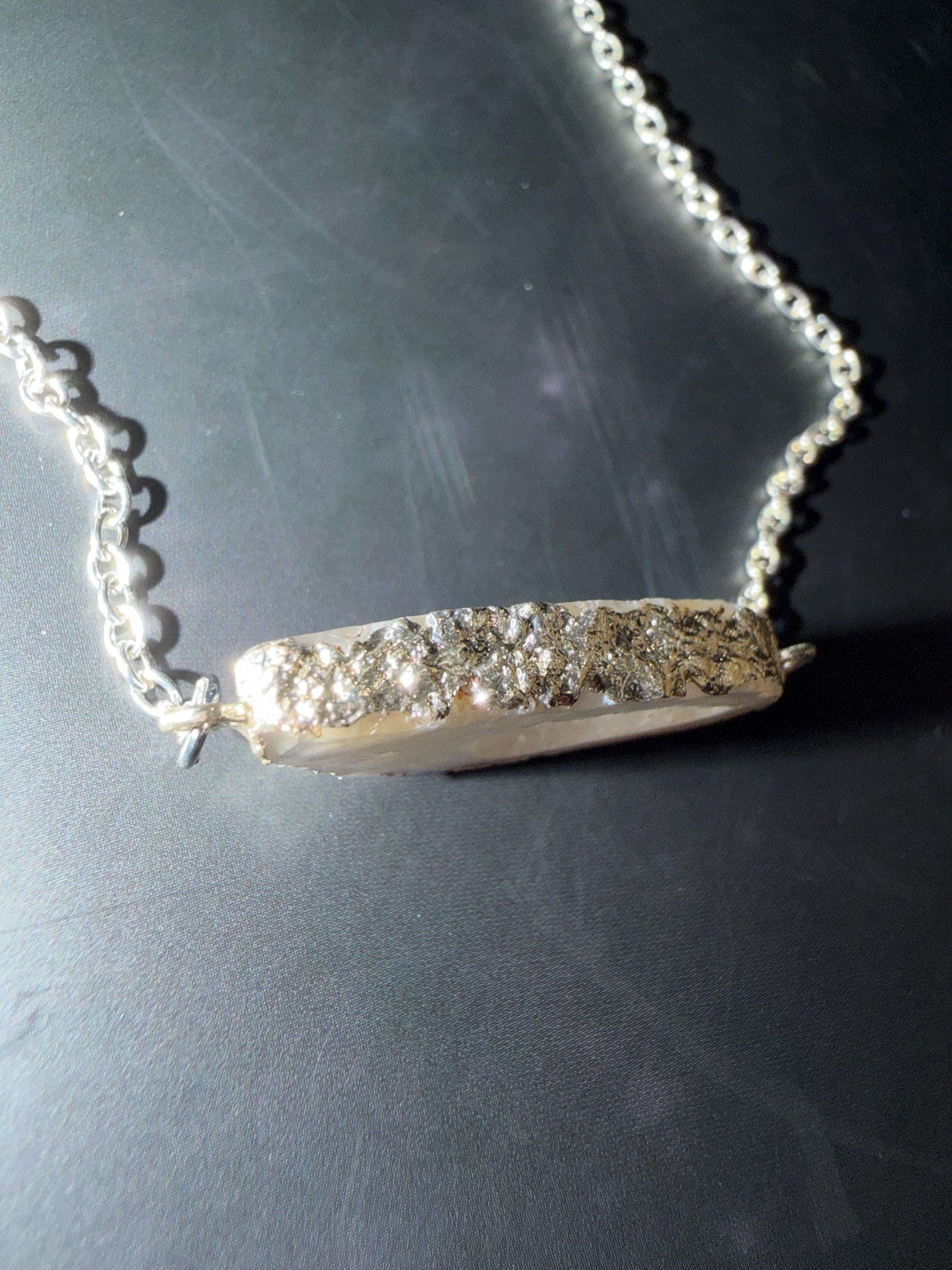 Silver necklace with a decorative clasp on a dark surface