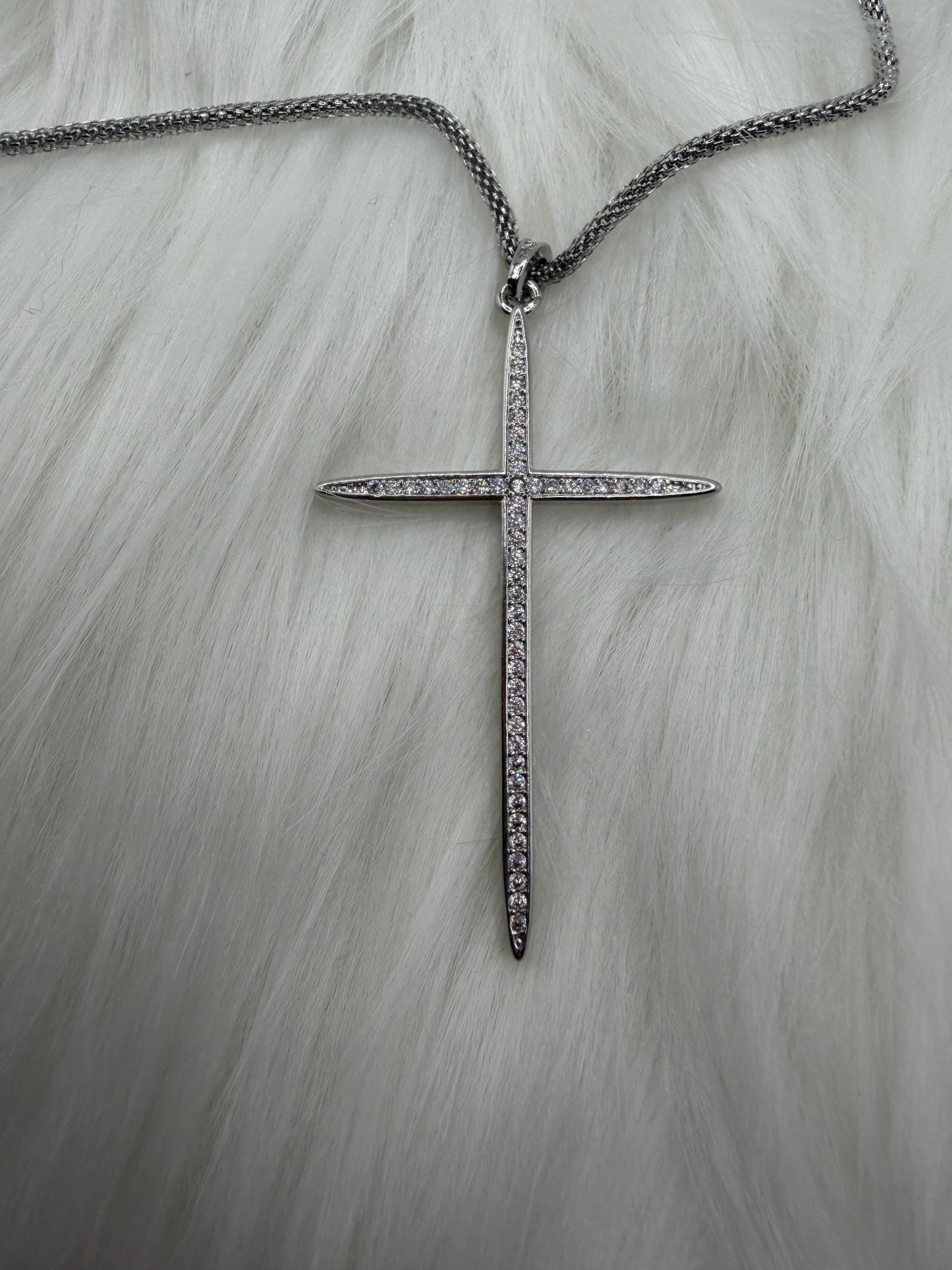 Silver cross necklace with chain on a light gray background