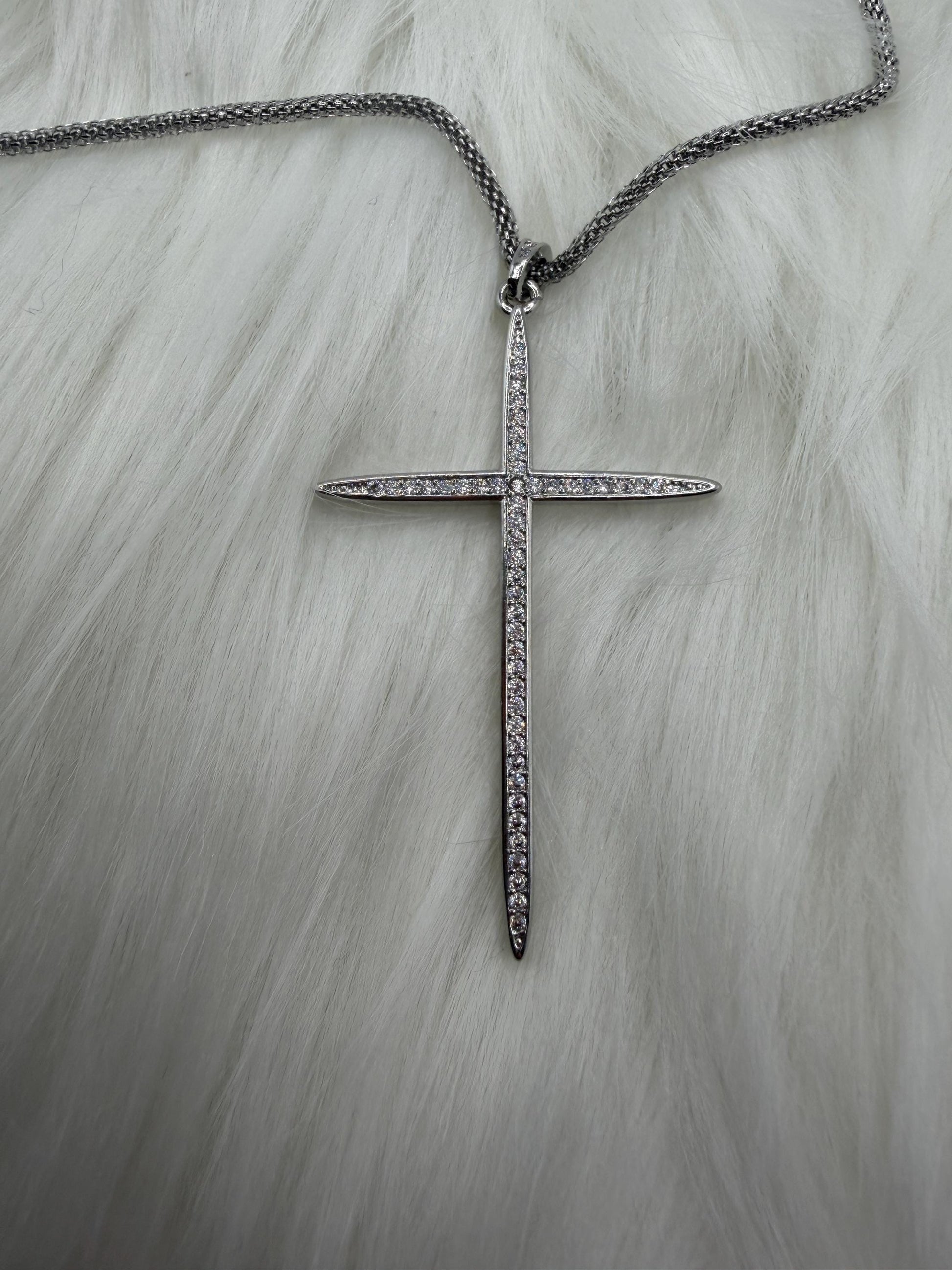 Silver cross necklace with chain on a light gray background