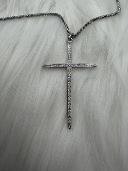 Silver cross necklace with chain on a light gray background
