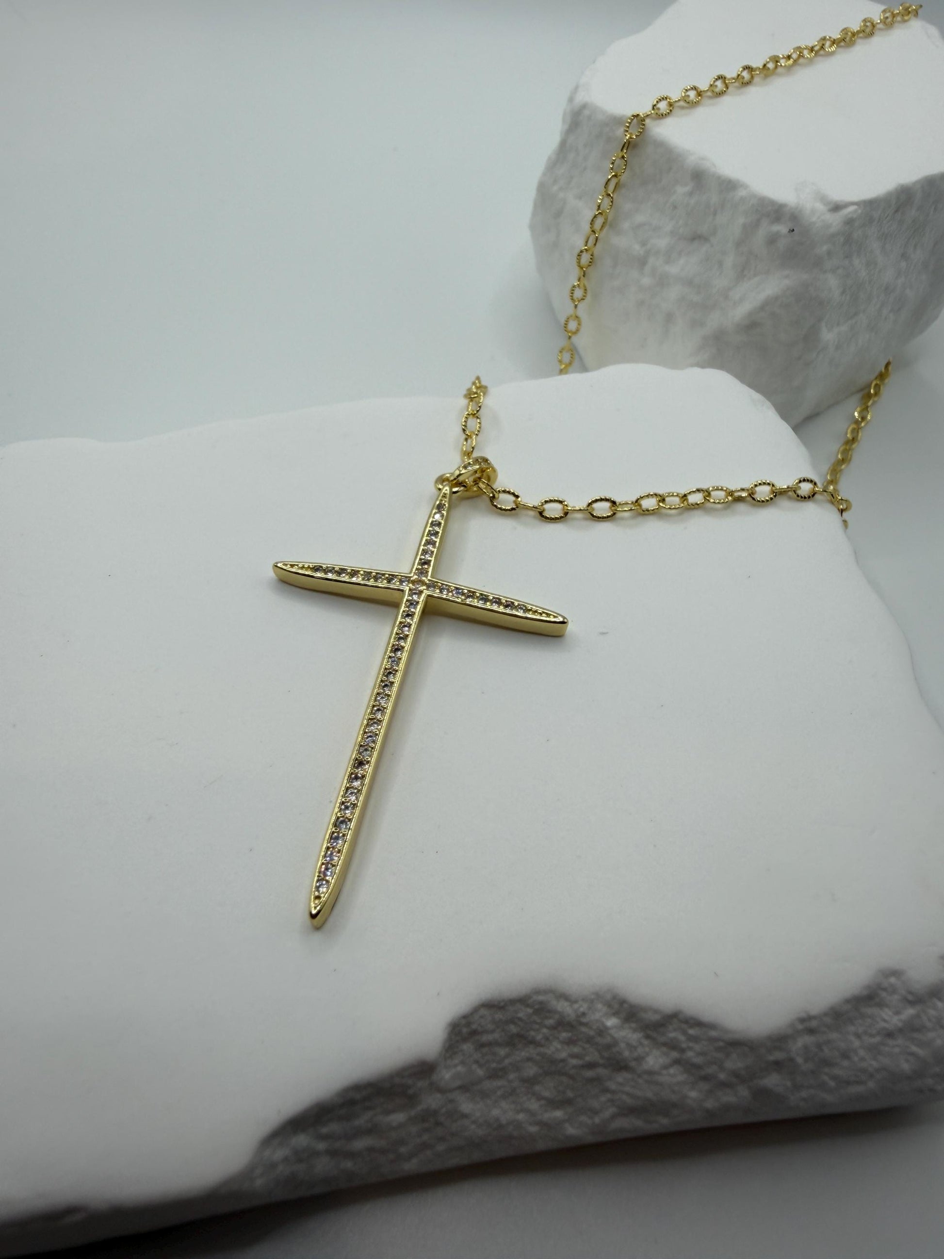 Gold cross necklace on a marble surface