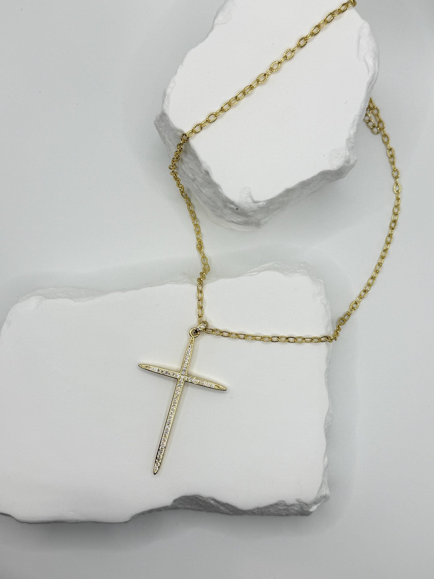 Gold cross necklace on a white stone surface