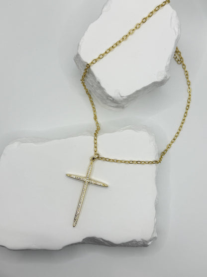 Gold cross necklace on a white stone surface