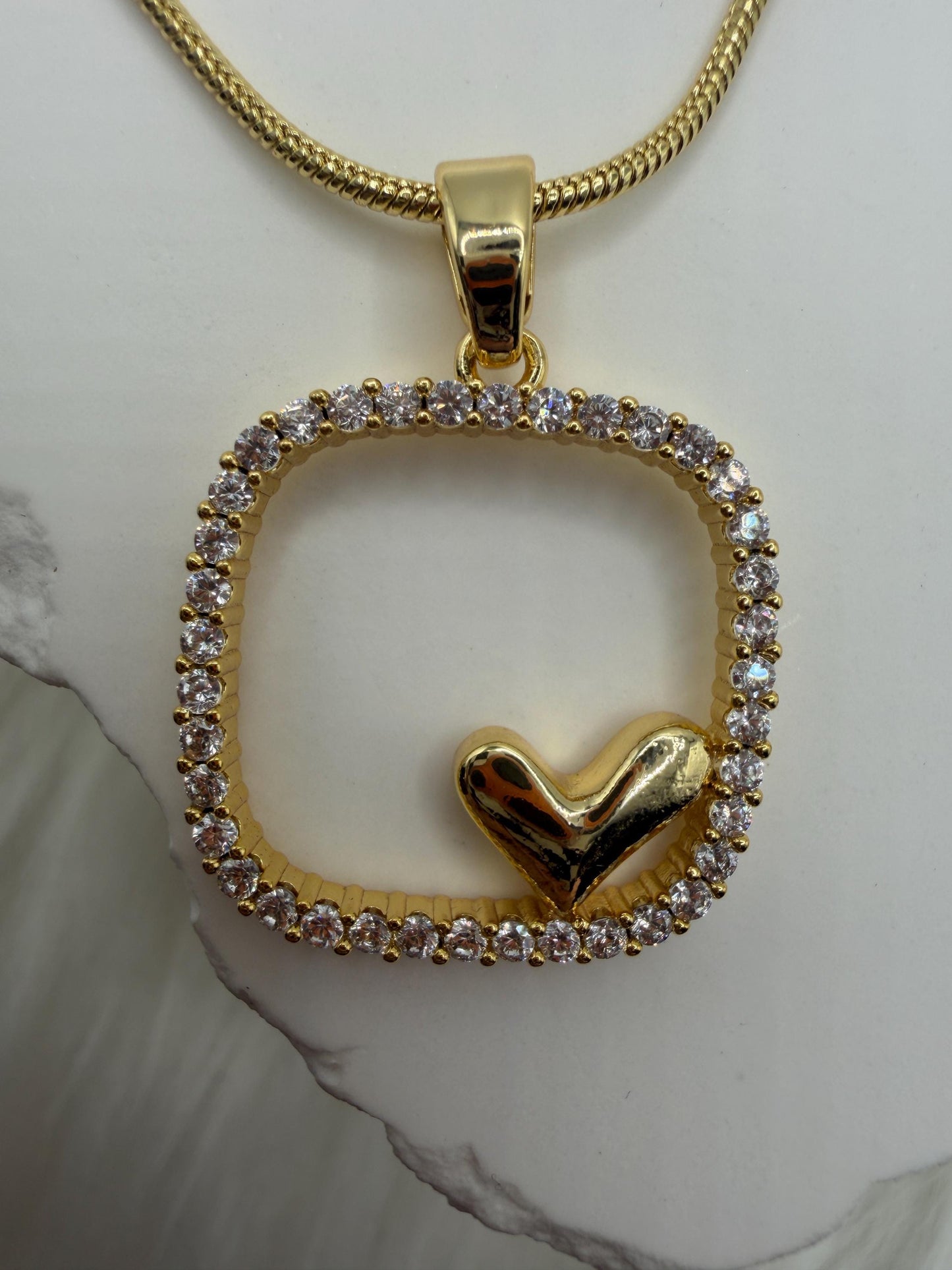 Gold pendant with heart design on a white background