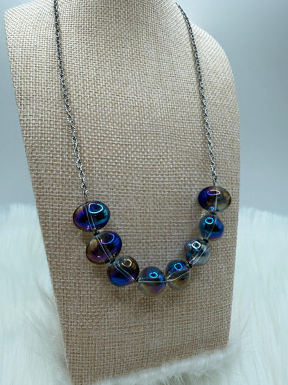 Necklace with blue and purple beads on a beige display stand.