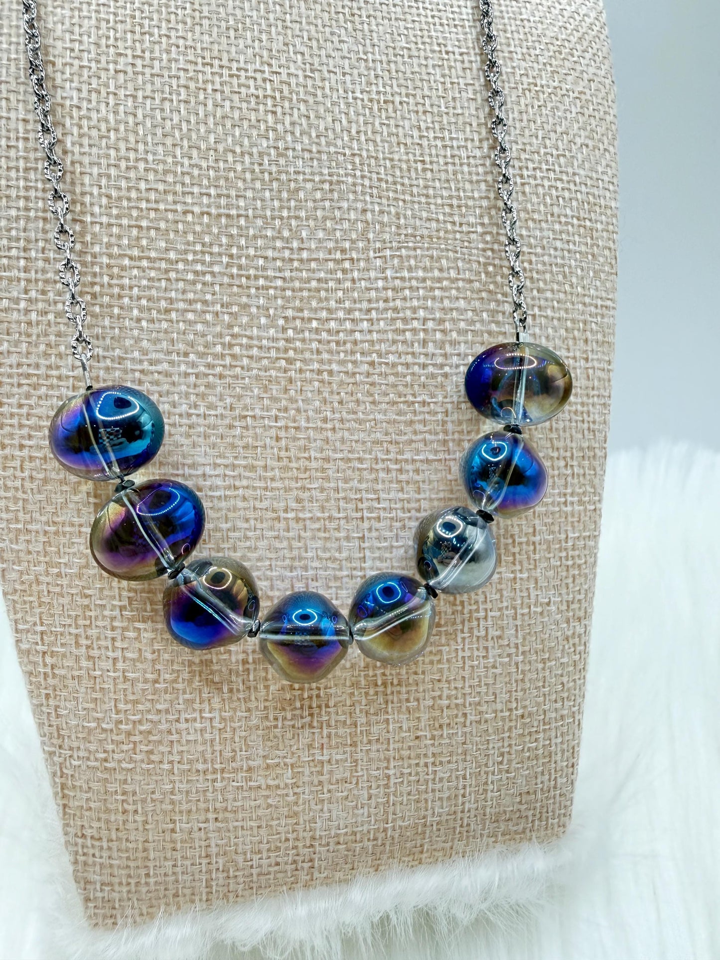 Necklace with blue and purple beaded design on a textured beige card.