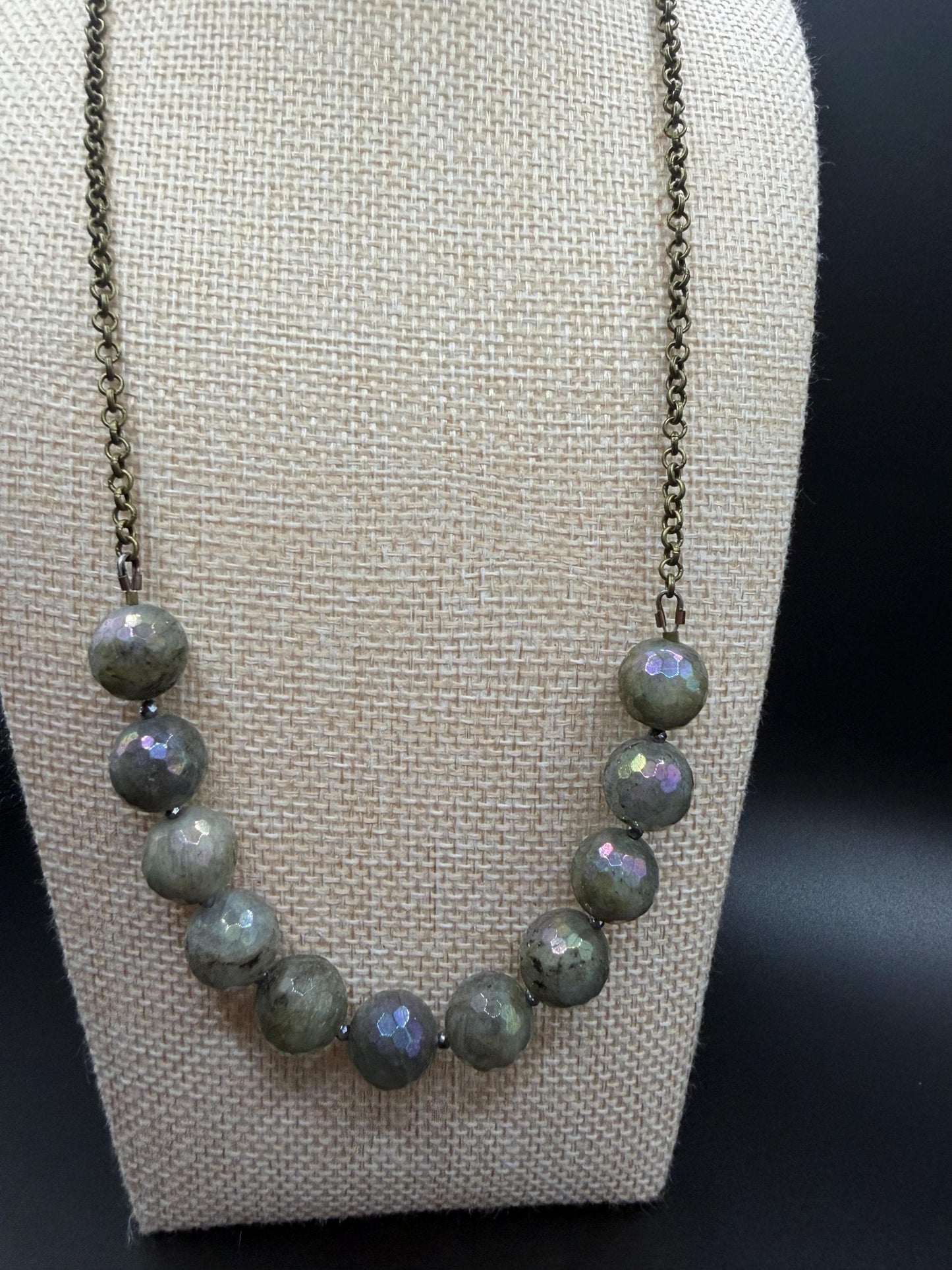 Necklace with Labradorite beads on a beige display stand.