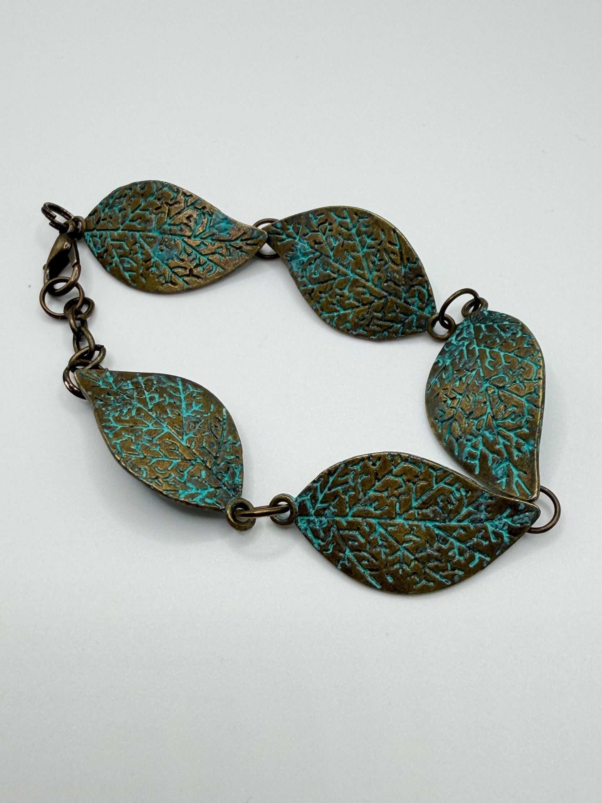 Brass bracelet with green patina on a white background