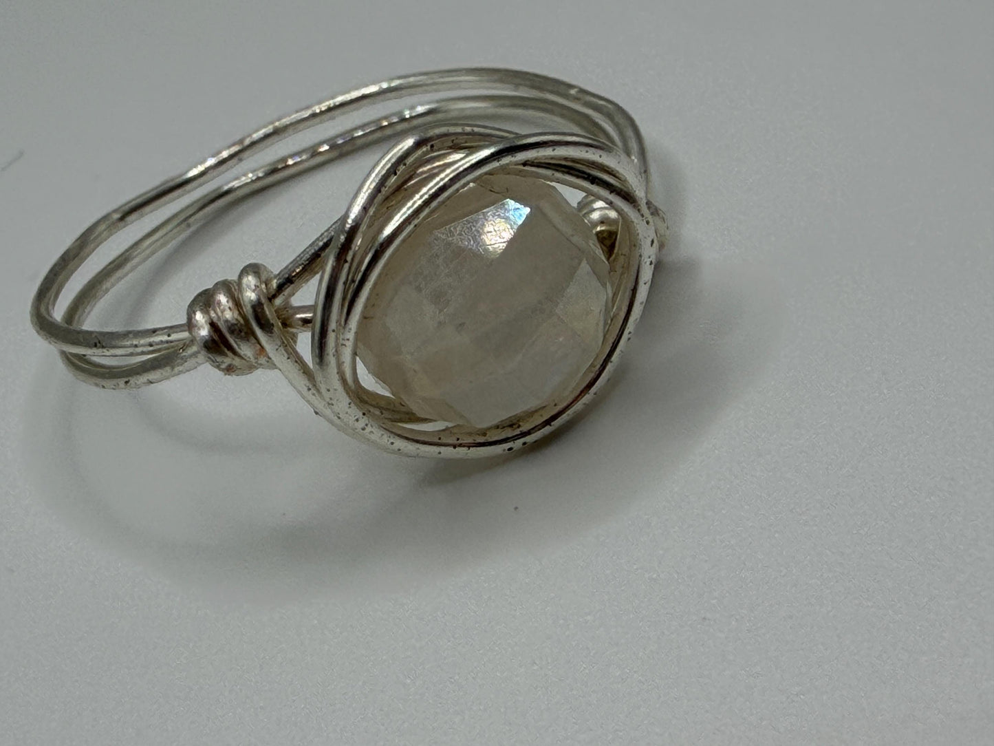 Silver wire-wrapped ring with a clear gemstone on a gray background