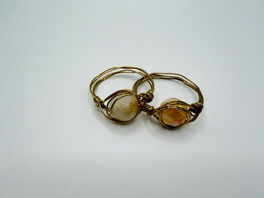Gold wire-wrapped ring with two stones on a white background