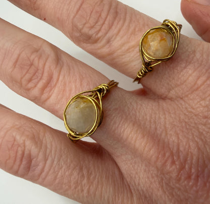 Gold rings with stone inlays on a person's fingers against a white background