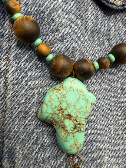 Necklace with turquoise stone and brown beads on denim fabric