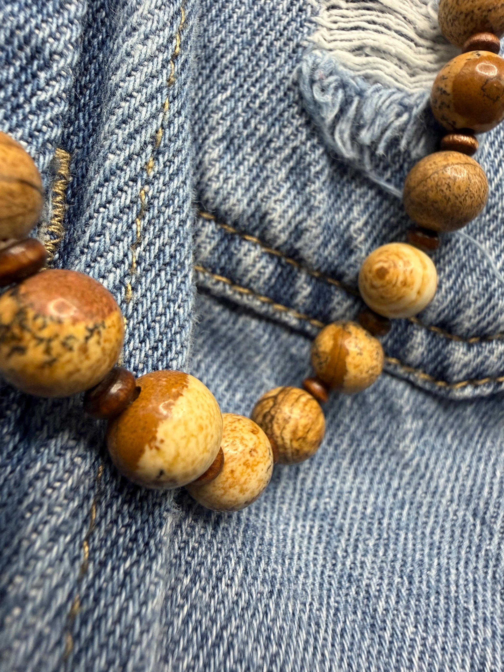Close-up of a wooden beaded necklace on blue denim fabric