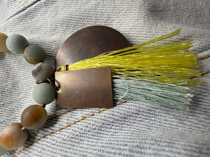 Necklace with beads and tassel on a textured fabric background