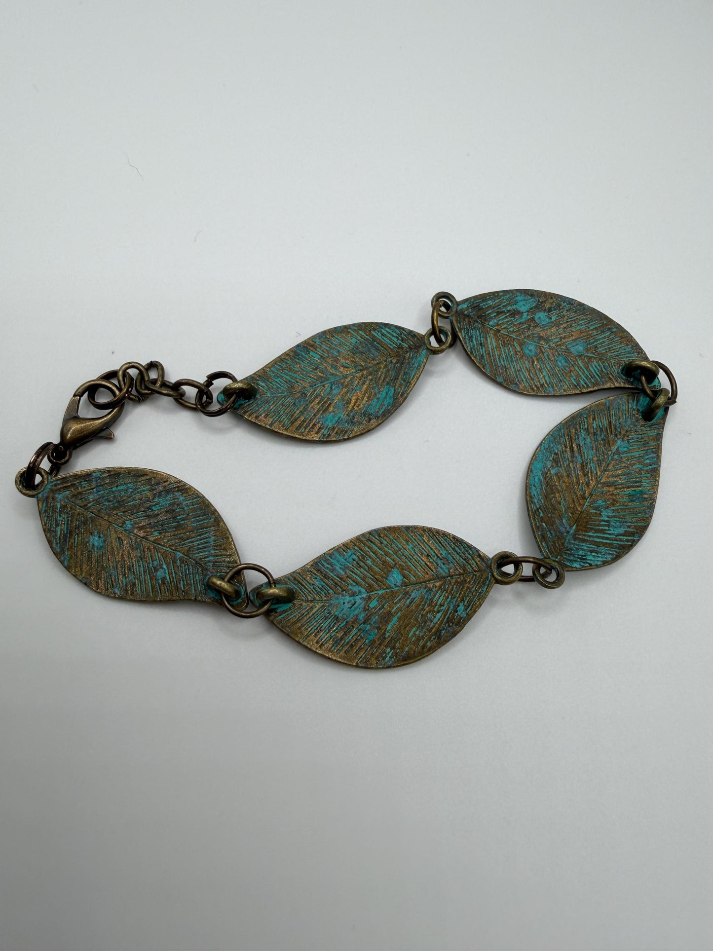 Brass bracelet with leaf-shaped links on a white background
