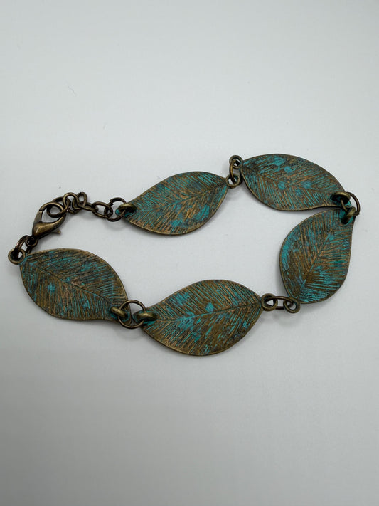 Brass bracelet with leaf-shaped links on a white background
