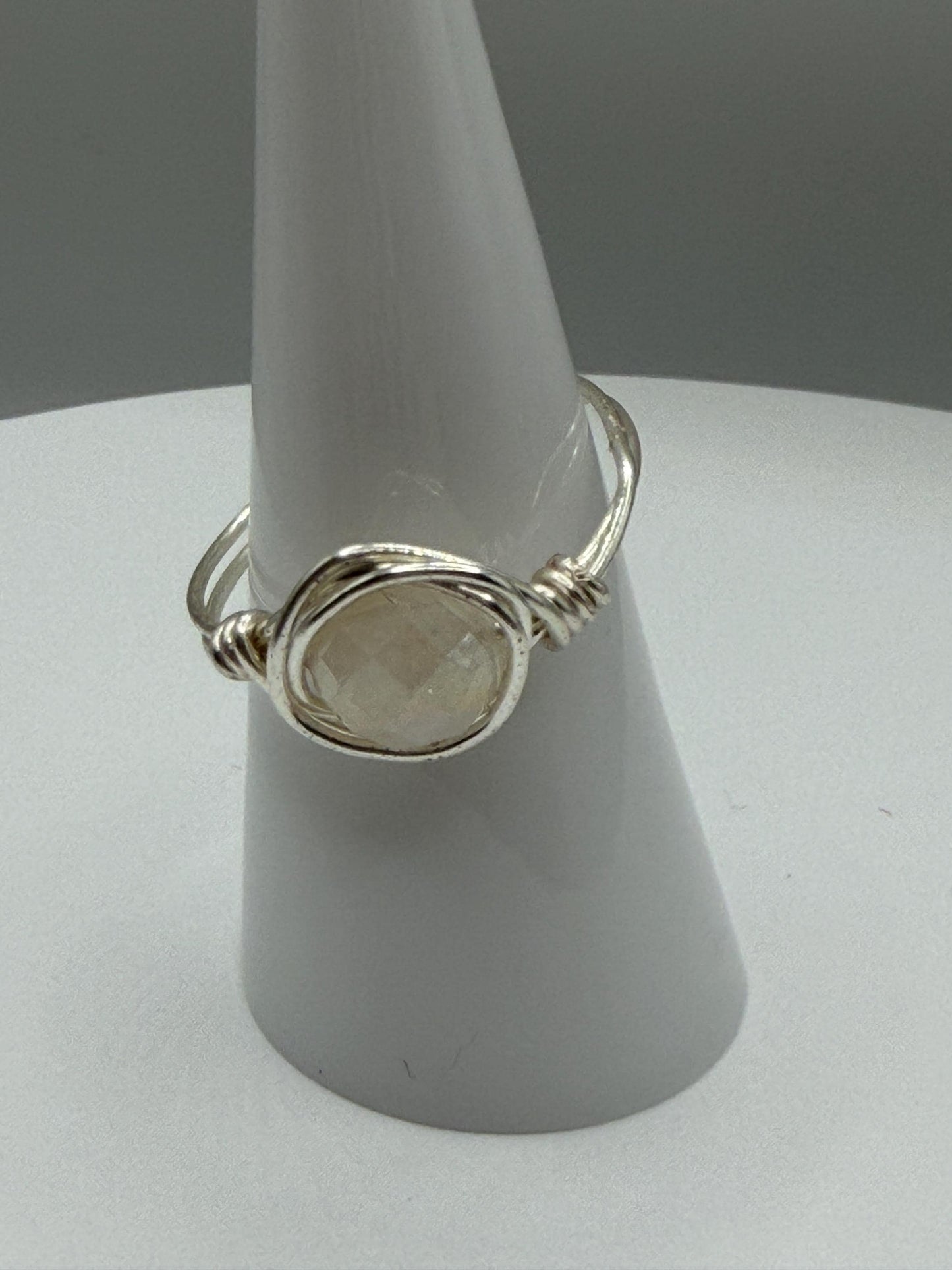 Silver ring with a stone on a gray stand against a gray background