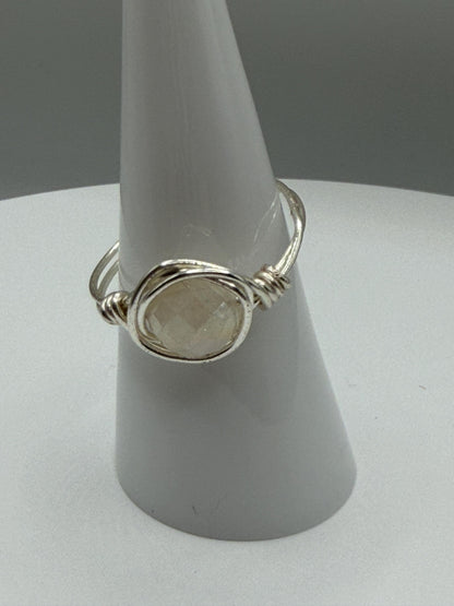 Silver ring with a stone on a gray stand against a gray background