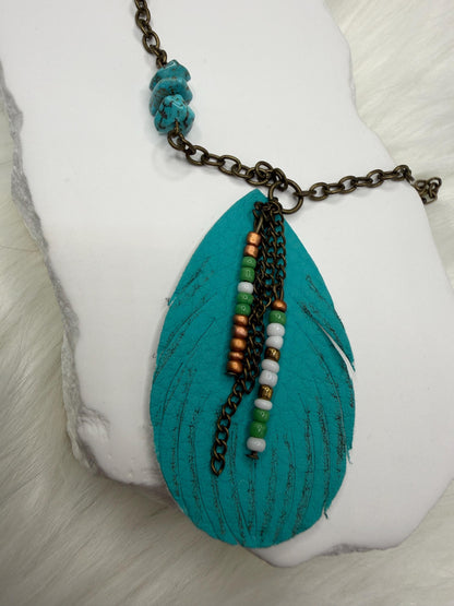 Turquoise pendant necklace with chain and beads on a white surface