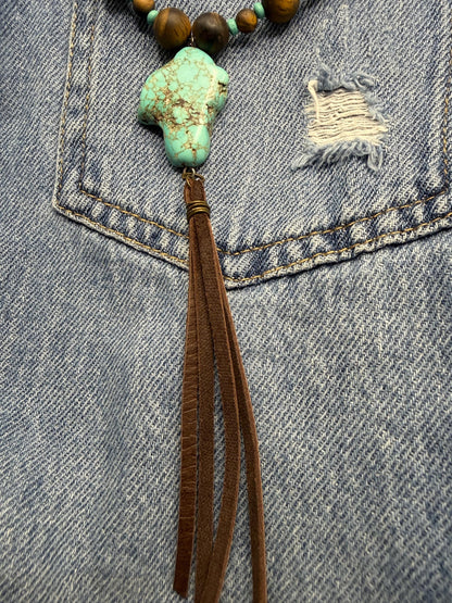 Necklace with turquoise pendant and brown tassel on denim fabric