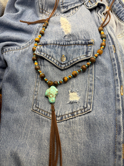 Necklace with beads and tassel hanging from a denim jacket pocket