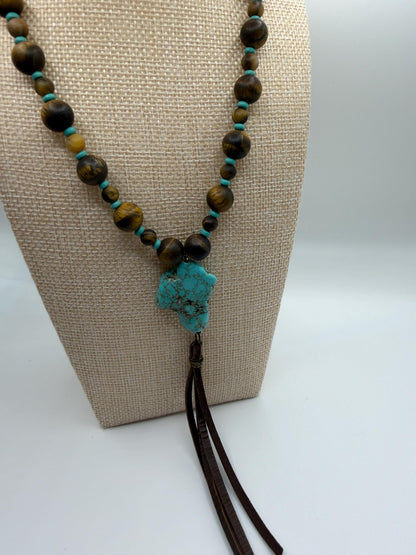 Necklace with turquoise stone pendant on a beige stand