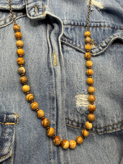Wooden beaded necklace draped over a denim jacket