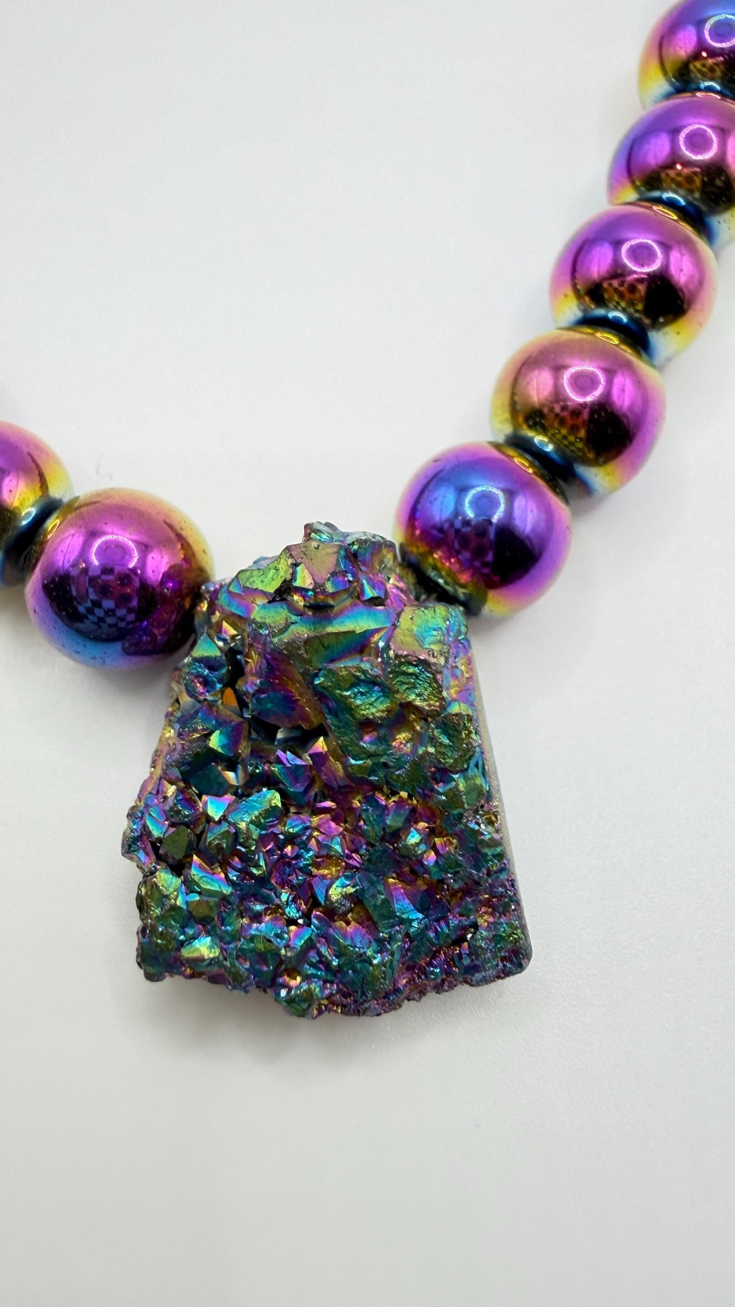 Necklace with colorful beaded strands and a large iridescent crystal pendant on a white background