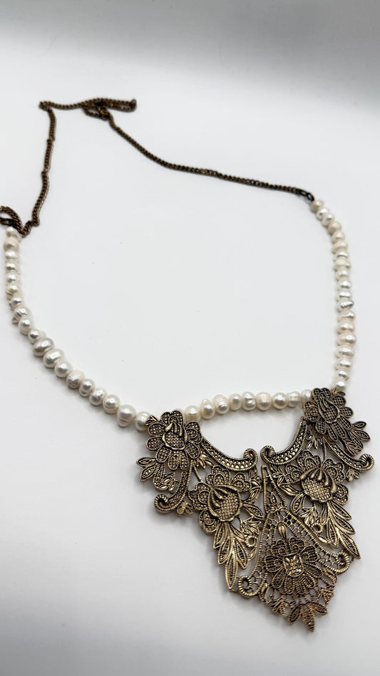 Necklace with floral metal pendant and pearl chain on a light background