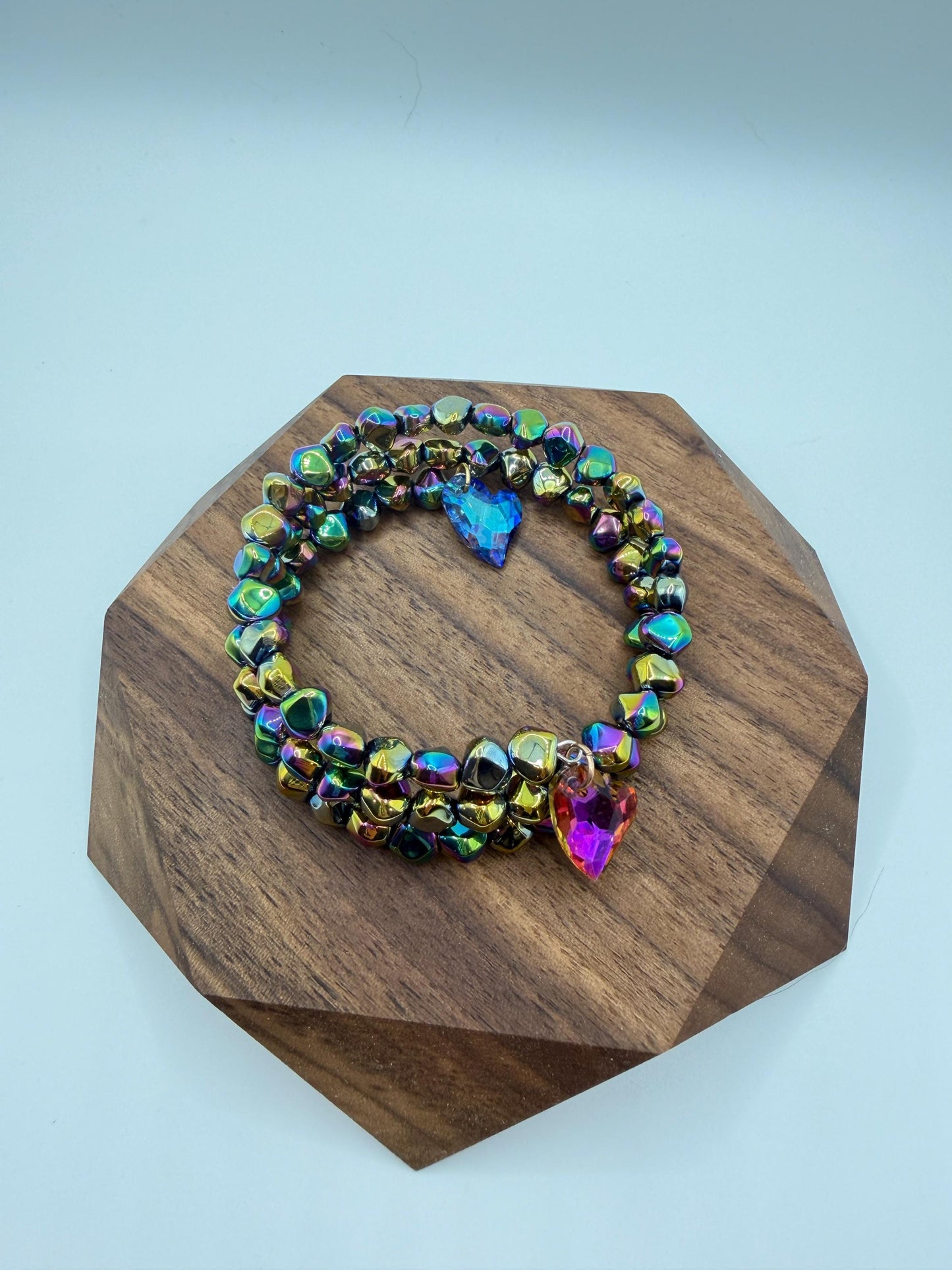 Multicolored beaded bracelet on a wooden stand with a light blue background