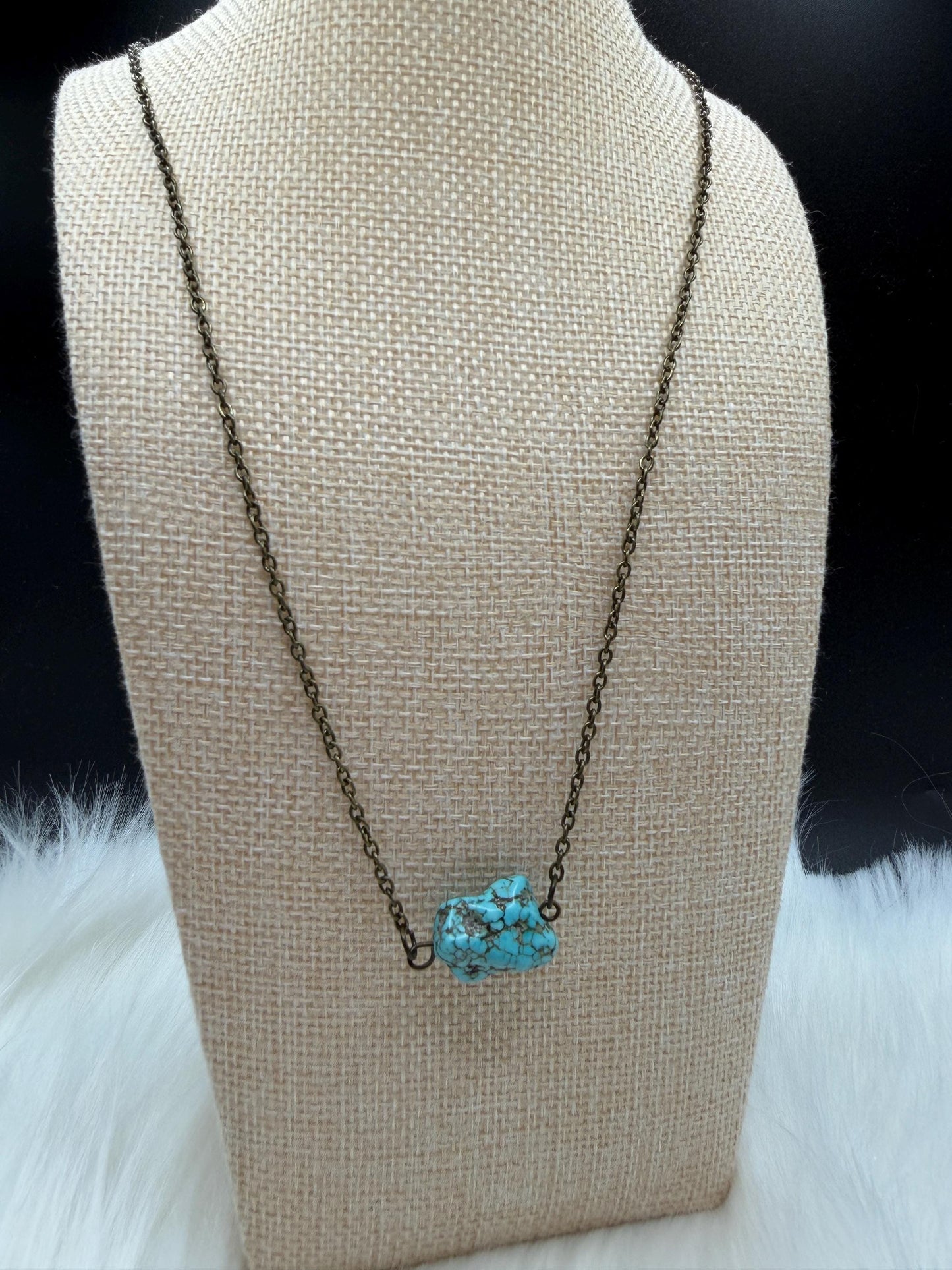 Necklace with a turquoise pendant on a mannequin bust against a dark background