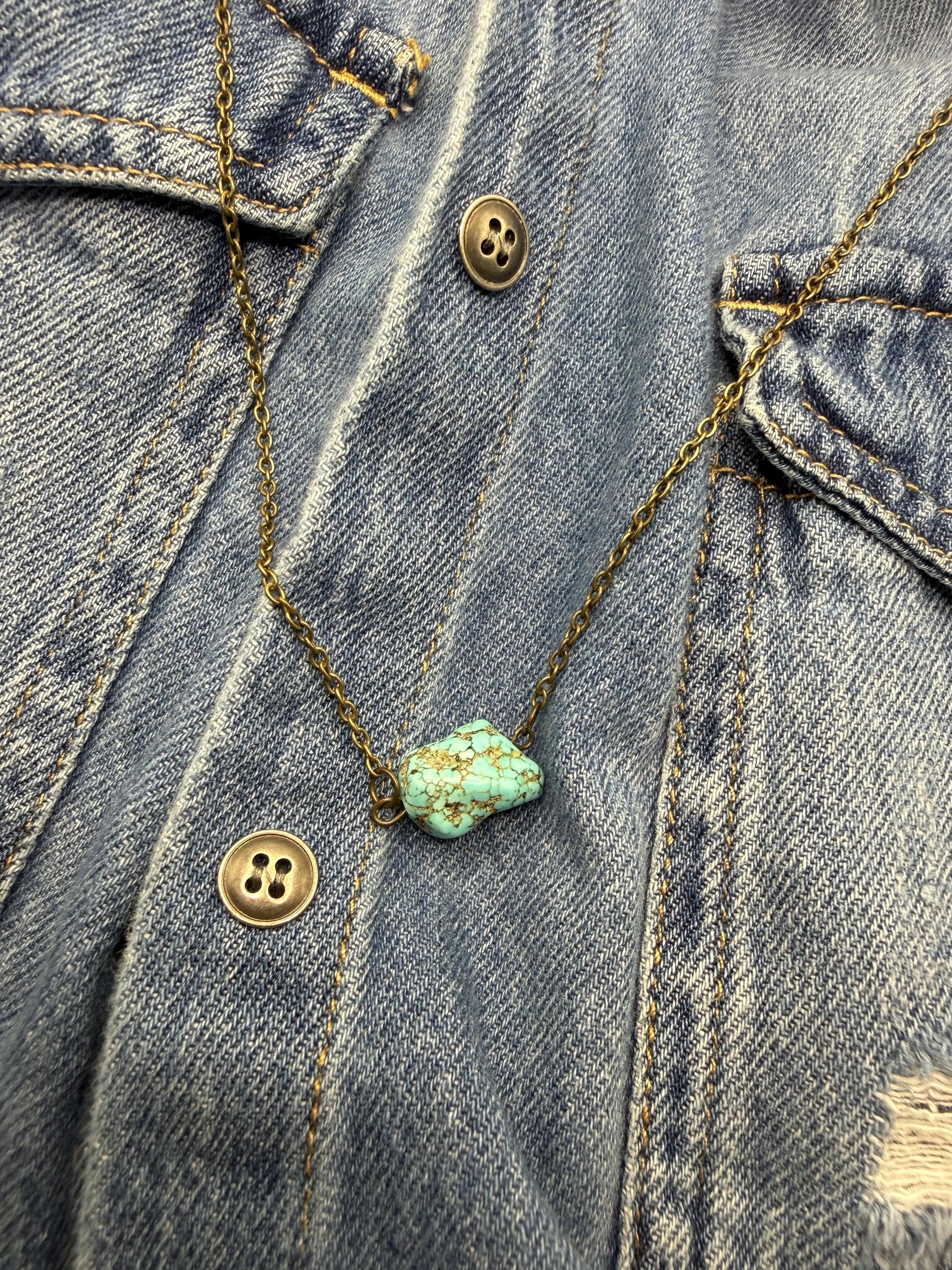 Turquoise stone necklace on a denim jacket