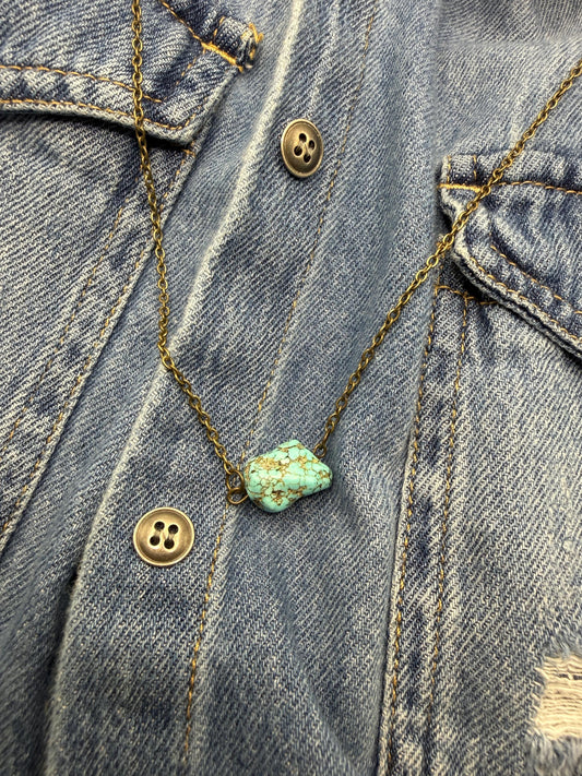 Turquoise stone necklace on a denim jacket