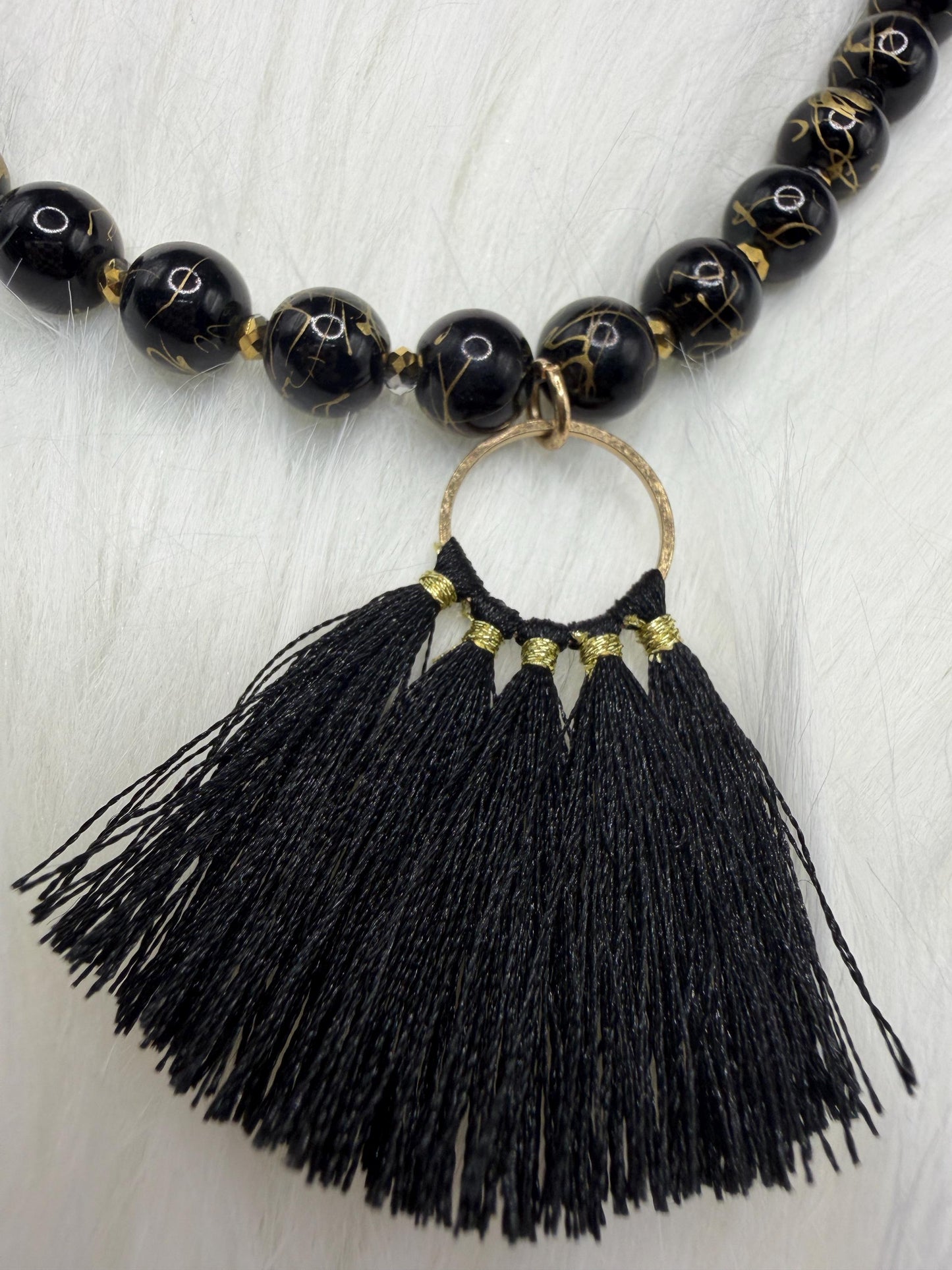 Necklace with black beads and tassel on a light wooden surface