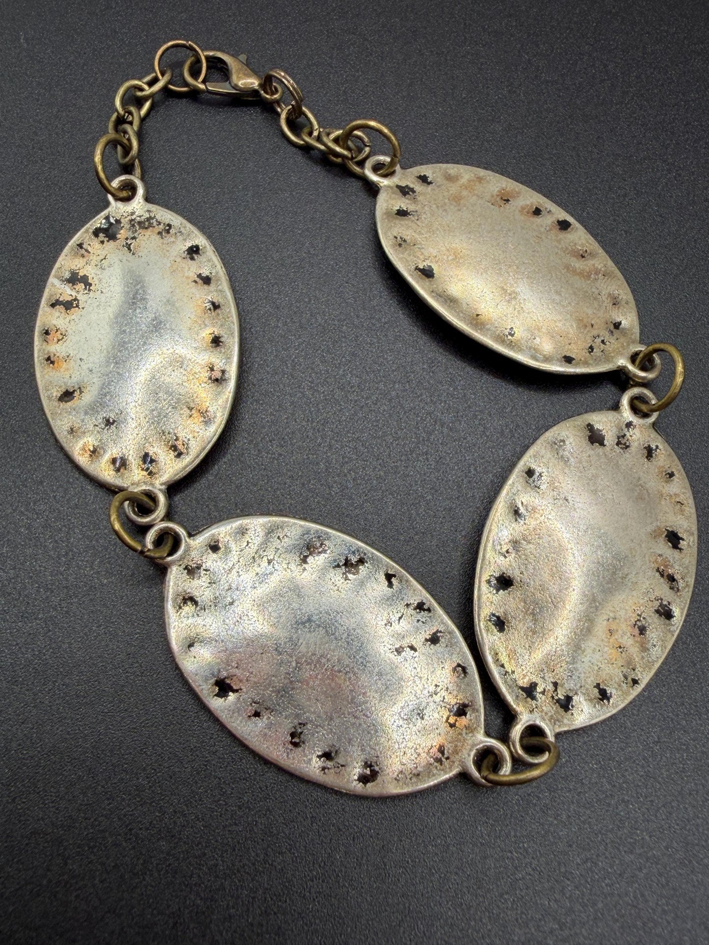 silver and bronze  bracelet  with oval pendants on a dark background