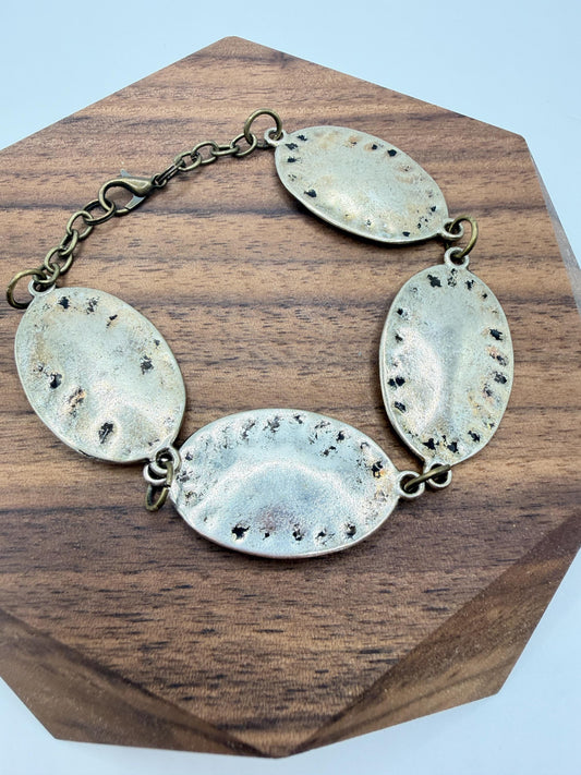 silver and bronze  bracelet with oval pendants on a wooden block