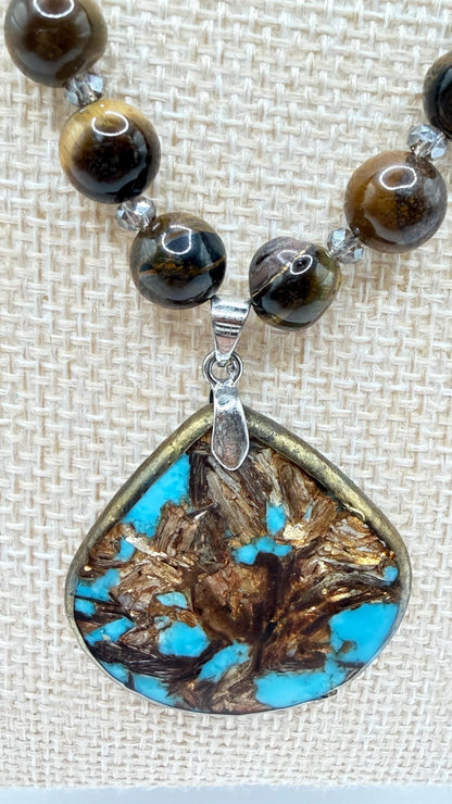Necklace with beads and a teardrop-shaped pendant featuring turquoise and brown colors.
