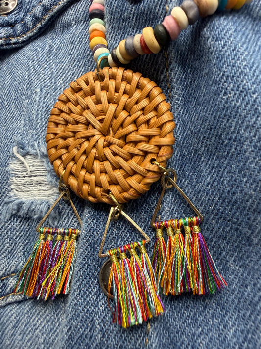 Woven round pendant with colorful tassels on a denim background