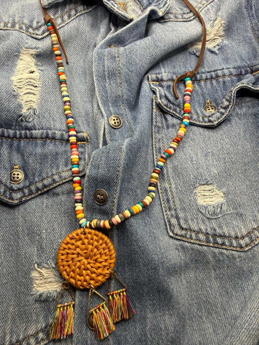 Colorful beaded necklace with a round pendant on a denim jacket