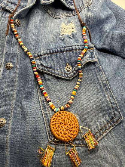 Colorful beaded necklace with a round orange pendant on a denim jacket.