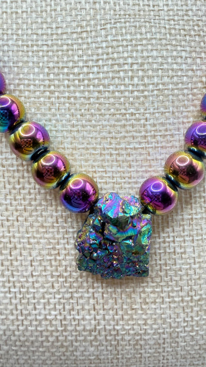 Necklace with iridescent beads and a central crystal-like pendant on a textured beige background
