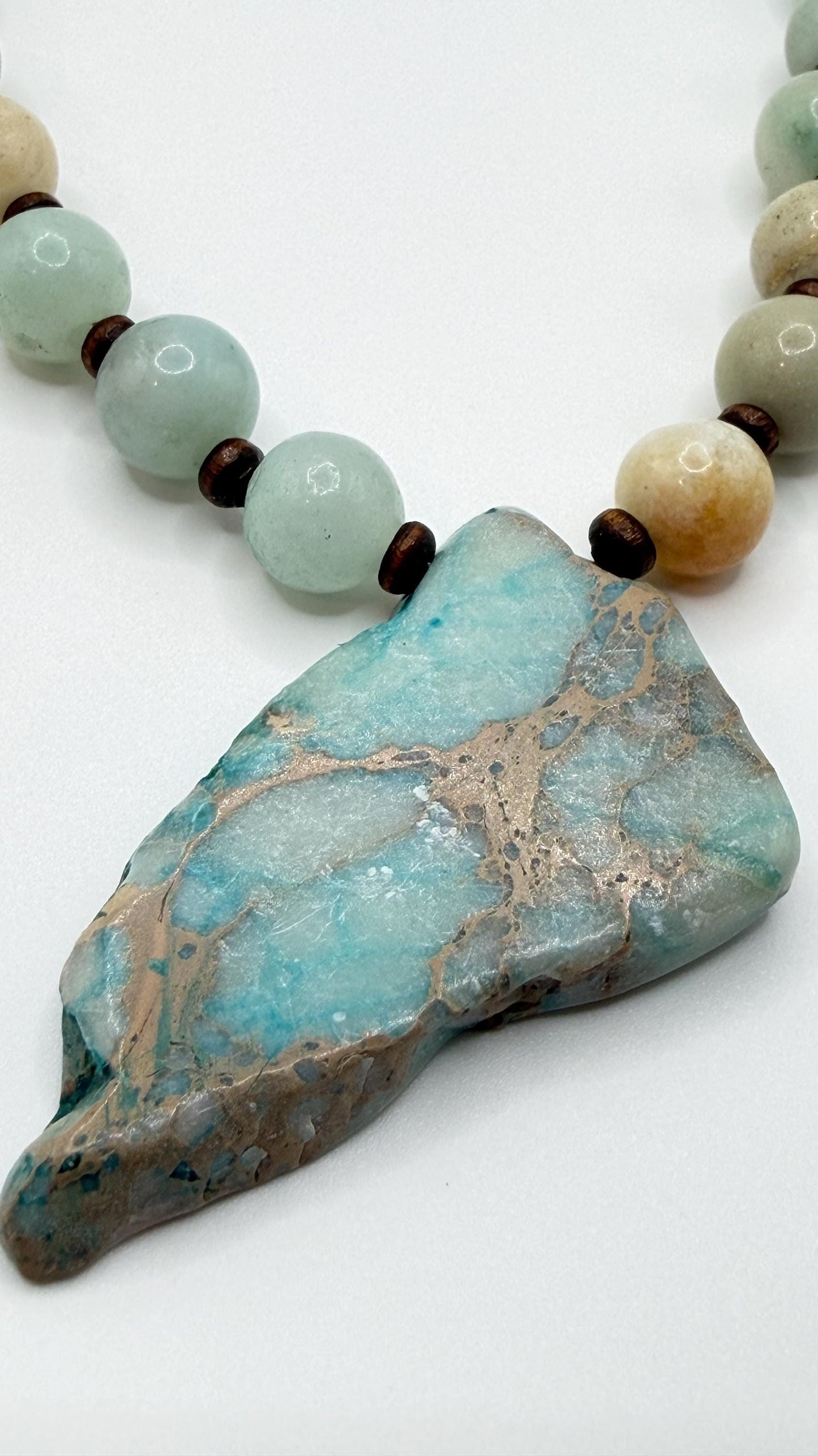 Necklace with large turquoise stone pendant and smaller beads on a white background